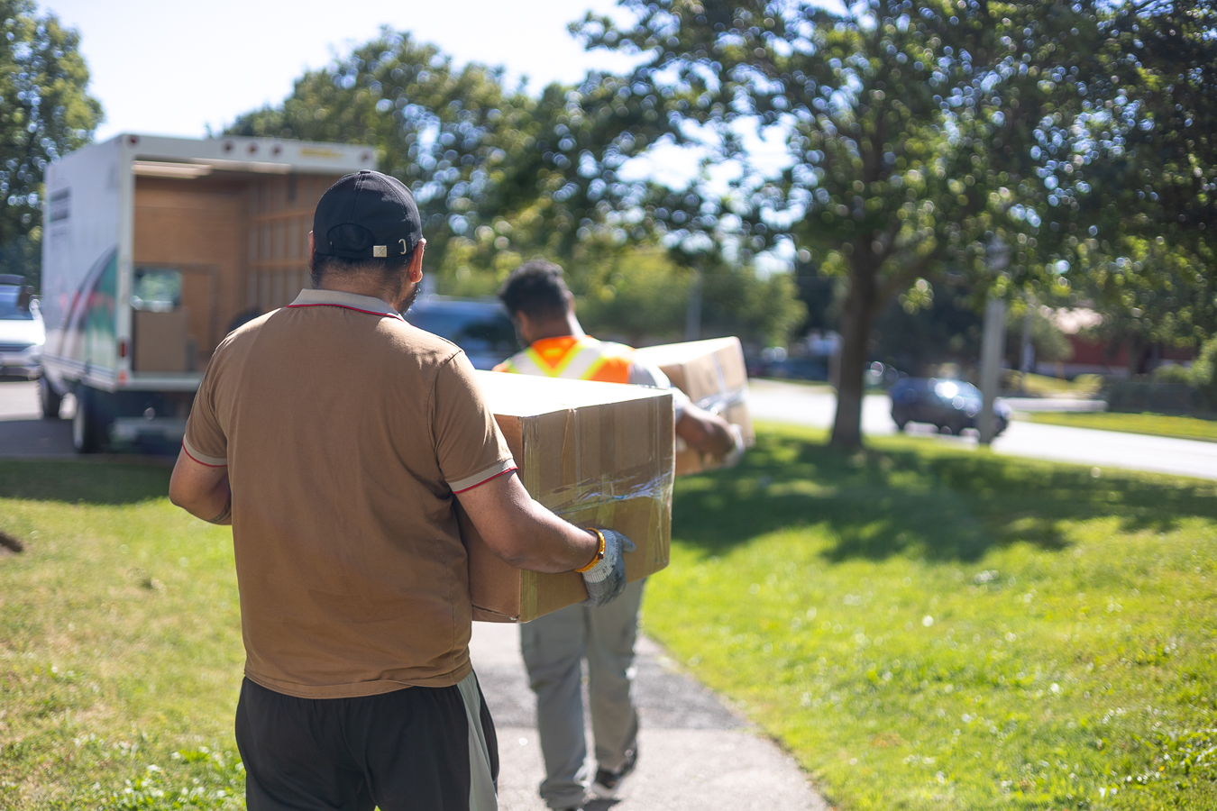 Rooster Movingz Inc. crew carrying a packed box to the moving truck