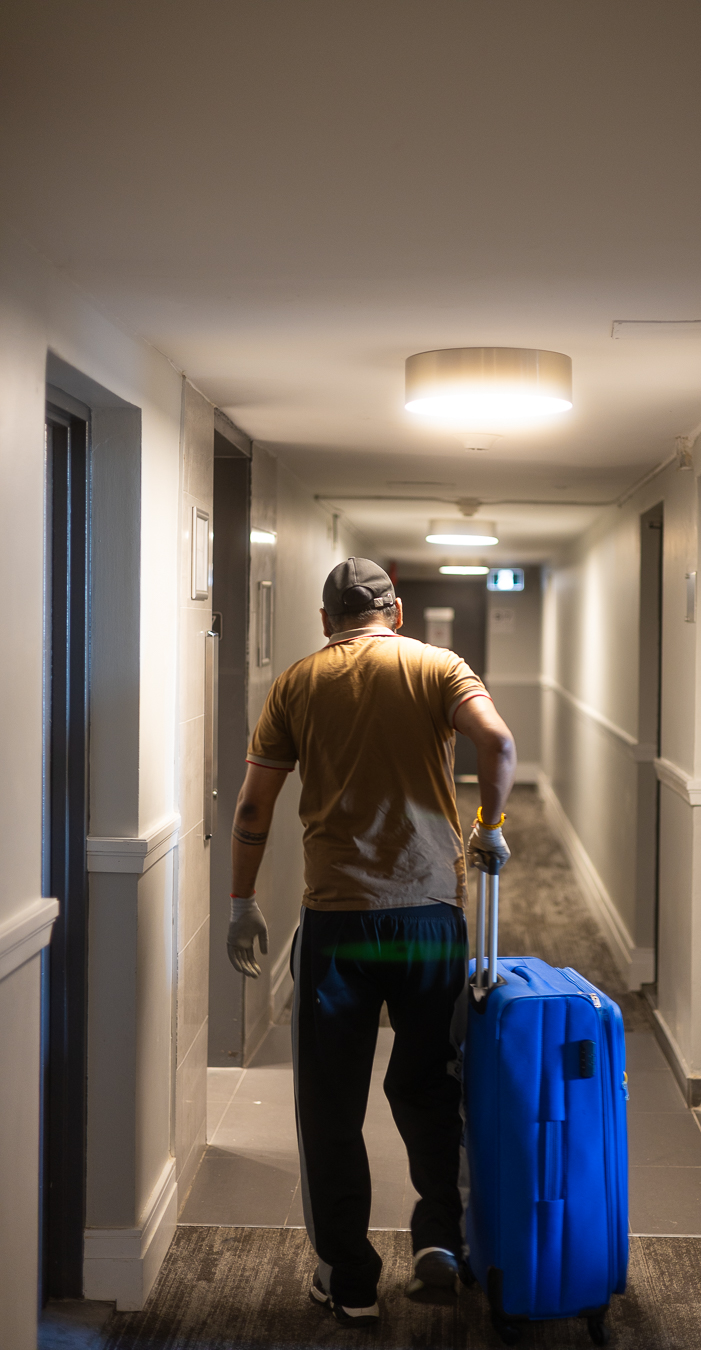 Rooster Movingz mover wheeling luggage down a condo corridor